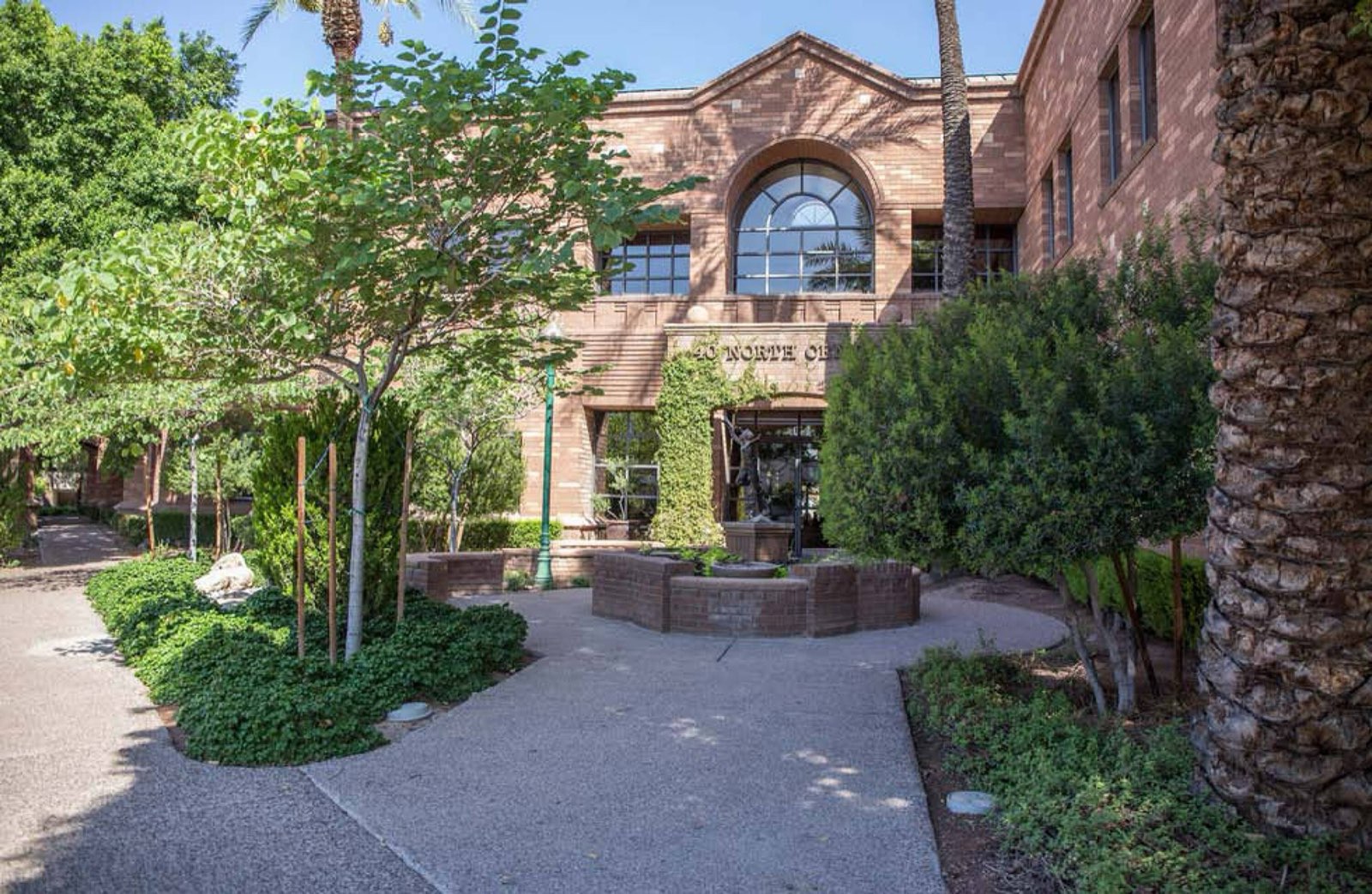 Tucker Law Group's brick office building in Mesa, with a shaded courtyard and palms